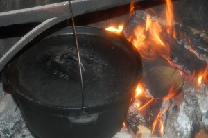 big pot over a fire with chicken, carrots, apples, onions & garlic